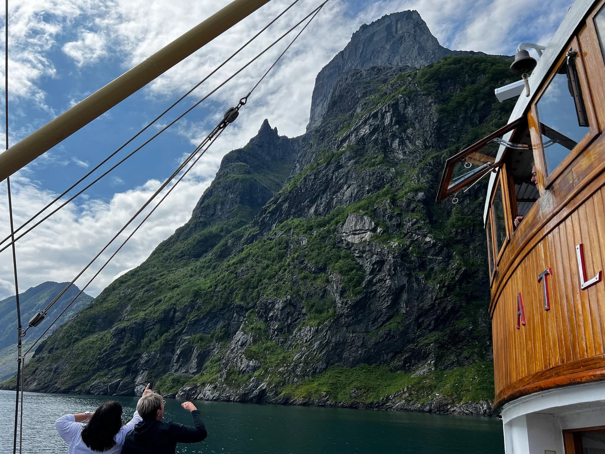 Gjester på dekk peker mot fjellet på en fjordtur fra Måløy